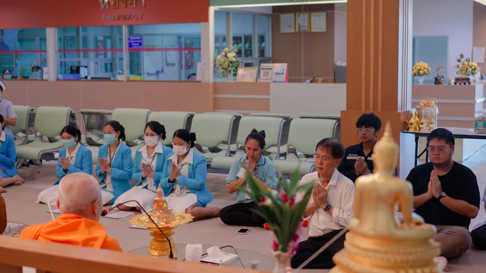 พระสงฆ์และเจ้าหน้าที่ในพิธีทำบุญ หน้าพระพุทธรูป